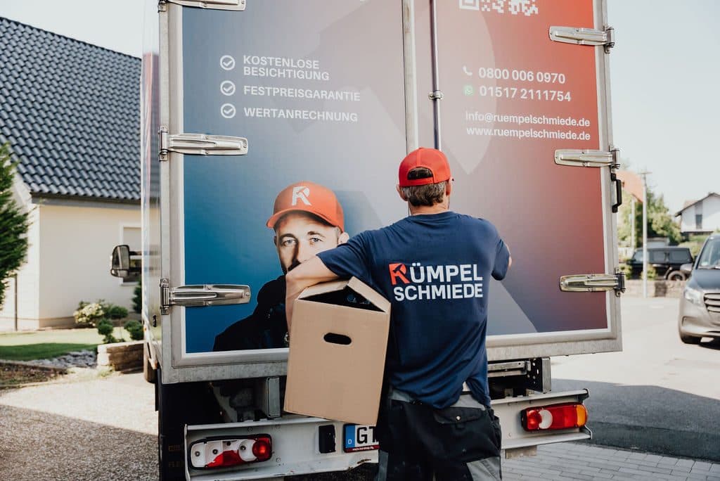 Mitarbeiter bringt einen Karton zum Transporter